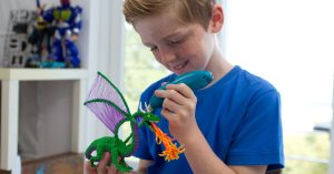 Dečak koristi 3D olovku za izradu zelene zmaj igračke od PLA filamenata