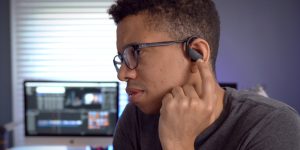 Muškarac koristi bežične slušalice Powerbeats PRO za montažu videa