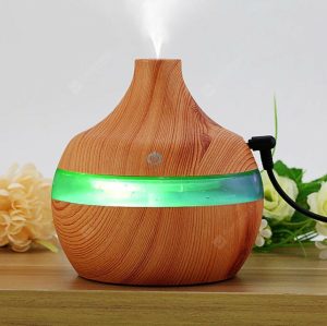 Mini aroma difuzor sa šarenim LED osvetljenjem uključenim, na drvenoj površini