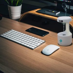 Ovlaživač vazduha na radnom stolu sa računarom, telefonima i biljkom