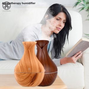 Žena čita knjigu dok pored nje na stolu radi ultrazvučni aroma difuzor u obliku vaze