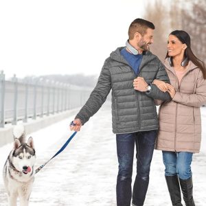 Mladi par koristi grejalice za vrat tokom šetnje sa psom dok je napolju hladno